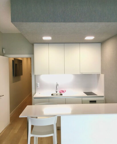 Mobiliario de cocina blanco integrado bajo un techo con revestimiento en el apartamento de Las Canteras de Interley.